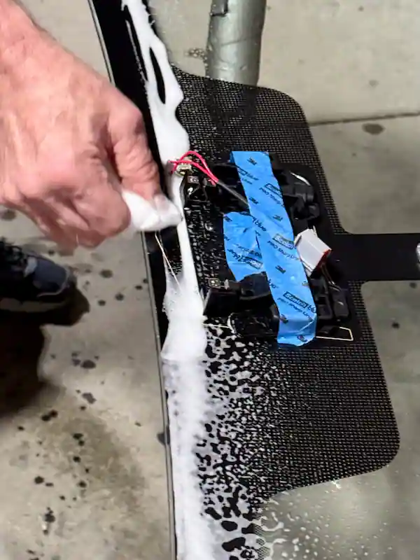 Auto glass technician wet scrubbing a windshield frit band prior to installation using GC-800 glass cleaner and beta scrubs, two steps in the Advanced Cure adhesive system