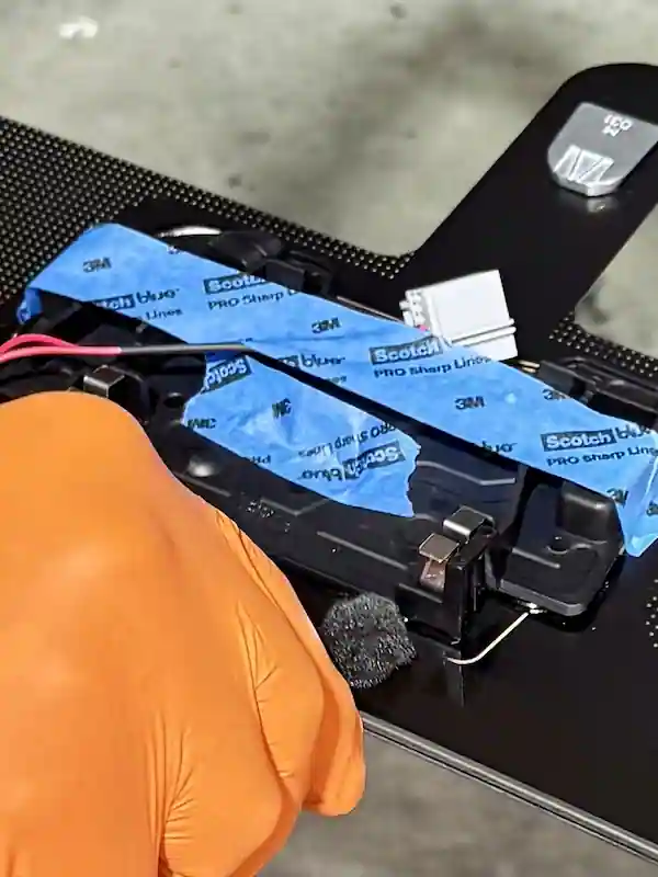 Auto glass technician applying 5504-G all in one primer to a windshield in the same area as the ADAS camera mount, lens area protected with blue tape until installed