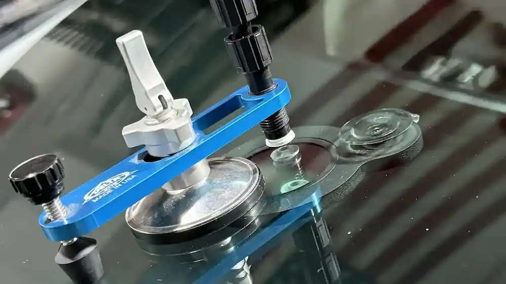 Windshield chip repair bridge mounted on a vehicle in the 123 Glass Company shop.