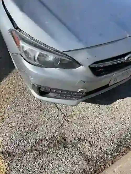 Body damage along the passenger's side of a Subaru Impreza after the hood flew open at highway speed.