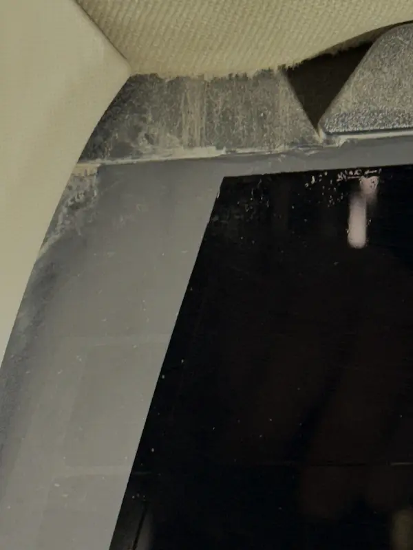 Dirt and water staining on the interior trim at the upper corner of the back glass — visually suggests a failed glass seal.