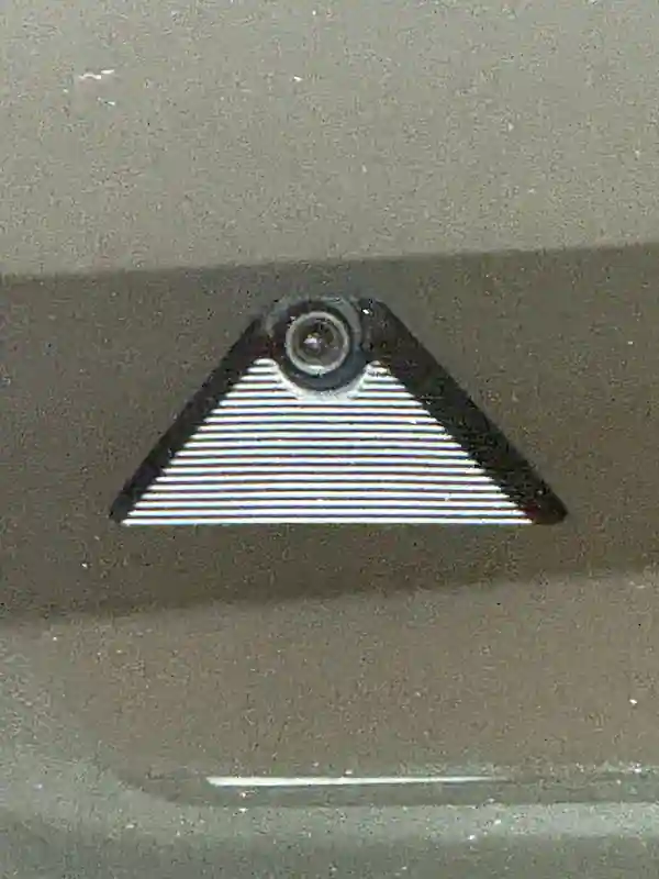 Forward facing ADAS camera mounted at the top center of a windshield showing the camera lens and mounting bracket on a third vehicle