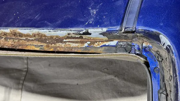 Corroded pinch weld at the driver side upper windshield corner of a 2004 Chevy Monte Carlo — rust exposed after glass removal.