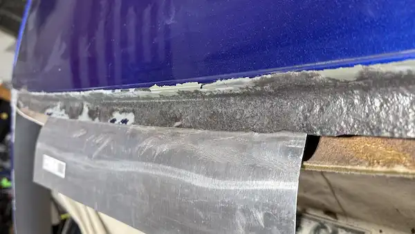 Top rail pinch weld during rust cleanup on a 2004 Chevy Monte Carlo — grinding in progress, not yet complete.