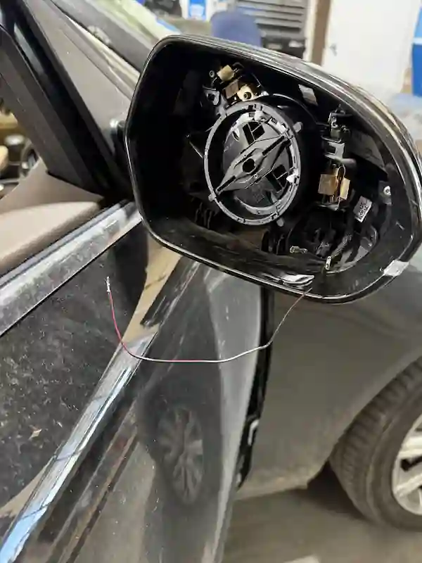 Damaged Audi side view mirror with internal mechanism exposed, brought in by customer for replacement at 123 Glass Company in Omaha