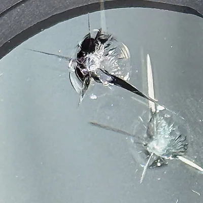 Compound combination windshield break — multiple intersecting chips from more than one impact point.