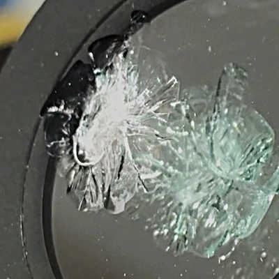 Starburst windshield chip — pulverized impact point with many cracks radiating outward.